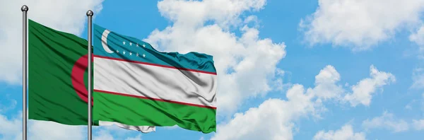 Bandera de Argelia y Uzbekistán ondeando en el viento contra el cielo azul nublado blanco juntos. Concepto diplomático, relaciones internacionales . — Foto de Stock