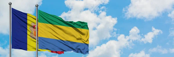 白い曇り青空に向かう風に揺れ、アンドラとガボンの旗が一緒に。外交概念、国際関係. — ストック写真