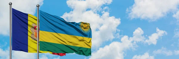 Bandera de Andorra y Ruanda ondeando en el viento contra el cielo azul nublado blanco juntos. Concepto diplomático, relaciones internacionales . — Foto de Stock