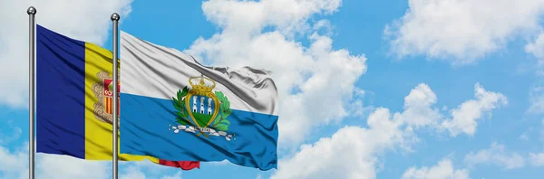 Bandera de Andorra y San Marino ondeando en el viento contra el cielo azul nublado blanco juntos. Concepto diplomático, relaciones internacionales . — Foto de Stock