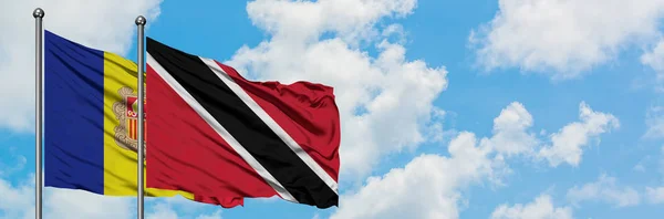 Andorra e a bandeira de Trinidad e Tobago agitando ao vento contra o céu azul nublado branco juntos. Conceito de diplomacia, relações internacionais . — Fotografia de Stock