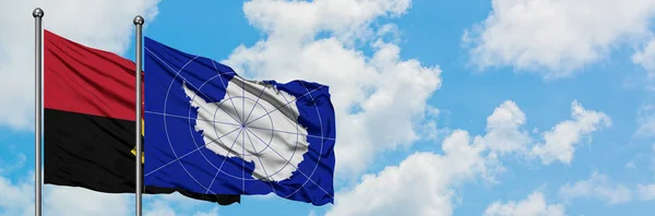 Bandera de Angola y la Antártida ondeando en el viento contra el cielo azul nublado blanco juntos. Concepto diplomático, relaciones internacionales . — Foto de Stock
