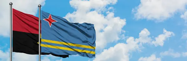 Bandera de Angola y Aruba ondeando en el viento contra el cielo azul nublado blanco juntos. Concepto diplomático, relaciones internacionales . —  Fotos de Stock