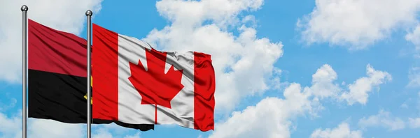 Bandera de Angola y Canadá ondeando en el viento contra el cielo azul nublado blanco juntos. Concepto diplomático, relaciones internacionales . — Foto de Stock