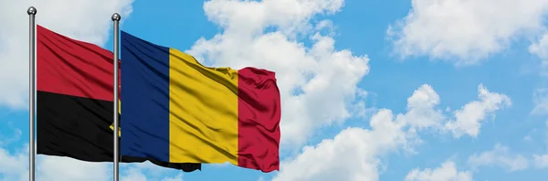 Angola en Tsjaad vlag zwaaien in de wind tegen witte bewolkte blauwe hemel samen. Diplomatie concept, internationale betrekkingen. — Stockfoto