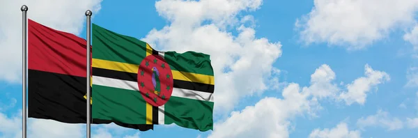 Angola and Dominica flag waving in the wind against white cloudy blue sky together. Diplomacy concept, international relations. — Stock Photo, Image