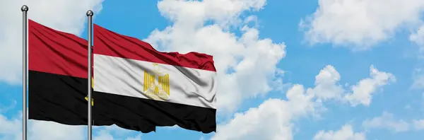 Bandera de Angola y Egipto ondeando en el viento contra el cielo azul nublado blanco juntos. Concepto diplomático, relaciones internacionales . — Foto de Stock