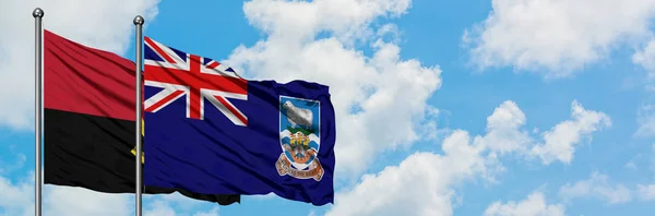 Bandera de Angola y las Islas Malvinas ondeando en el viento contra el cielo azul nublado blanco juntos. Concepto diplomático, relaciones internacionales . — Foto de Stock