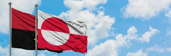 Angola a Grónská vlajka mávali ve větru proti bíle zatažené modré obloze. Diplomacie, mezinárodní vztahy. — Stock fotografie