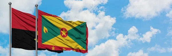 Bandera de Angola y Granada ondeando en el viento contra el cielo azul nublado blanco juntos. Concepto diplomático, relaciones internacionales . — Foto de Stock