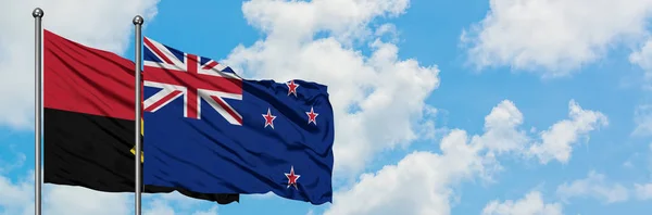安哥拉和新西兰国旗在风中飘扬，与白云蓝天相一起。外交概念、国际关系. — 图库照片