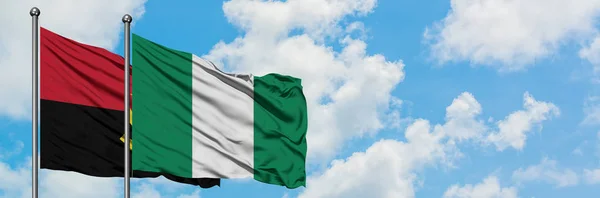 Angola and Nigeria flag waving in the wind against white cloudy blue sky together. Diplomacy concept, international relations.