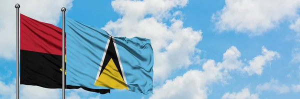 Angola en Saint Lucia vlag zwaaien in de wind tegen witte bewolkte blauwe hemel samen. Diplomatie concept, internationale betrekkingen. — Stockfoto
