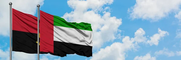 Bandera de Angola y Emiratos Árabes Unidos ondeando en el viento contra el cielo azul nublado blanco juntos. Concepto diplomático, relaciones internacionales . — Foto de Stock