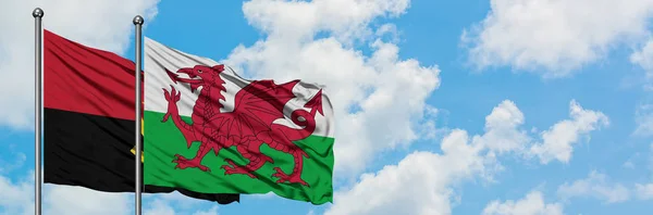 Angola en Wales vlag zwaaien in de wind tegen witte bewolkte blauwe hemel samen. Diplomatie concept, internationale betrekkingen. — Stockfoto