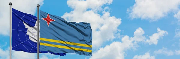 Antártida y la bandera de Aruba ondeando en el viento contra el cielo azul nublado blanco juntas. Concepto diplomático, relaciones internacionales . —  Fotos de Stock