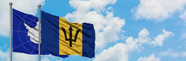 A Antártida e a bandeira de Barbados agitando no vento contra o céu azul nublado branco juntos. Conceito de diplomacia, relações internacionais . — Fotografia de Stock