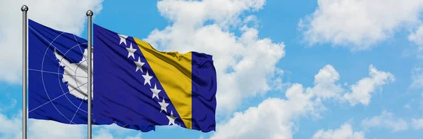 Bandera de la Antártida y Bosnia Herzegovina ondeando en el viento contra el cielo azul nublado blanco juntos. Concepto diplomático, relaciones internacionales . — Foto de Stock