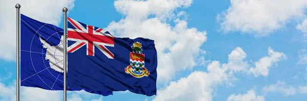 Antarktisz és Kajmán-szigetek zászló integetett a szél ellen, fehér felhős kék ég együtt. Diplomáciai koncepció, nemzetközi kapcsolatok. — Stock Fotó