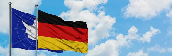 Antartide e Germania sventolano bandiera nel vento contro bianco cielo blu nuvoloso insieme. Concetto di diplomazia, relazioni internazionali . — Foto Stock