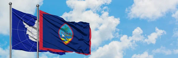 Bandera de la Antártida y Guam ondeando en el viento contra el cielo azul nublado blanco juntos. Concepto diplomático, relaciones internacionales . — Foto de Stock