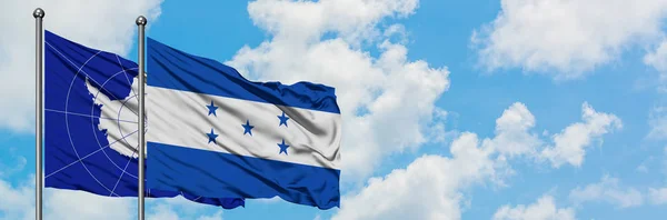 Bandera de la Antártida y Honduras ondeando en el viento contra el cielo azul nublado blanco juntos. Concepto diplomático, relaciones internacionales . — Foto de Stock