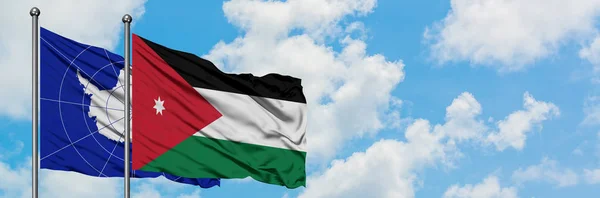 Bandera de la Antártida y Jordania ondeando en el viento contra el cielo azul nublado blanco juntos. Concepto diplomático, relaciones internacionales . — Foto de Stock