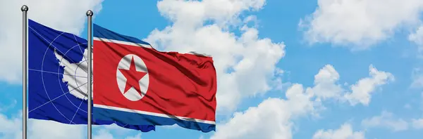 Η σημαία της Ανταρκτικής και της Βόρειας Κορέας κουνώντας τον άνεμο ενάντια στο λευκό συννεφιασμένο γαλάζιο του ουρανού μαζί. Φιλοσοφία της διπλωματίας, διεθνείς σχέσεις. — Φωτογραφία Αρχείου