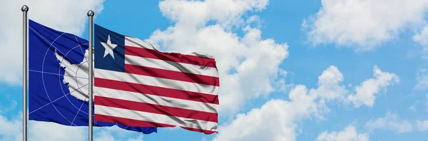 Bandeira da Antártida e Libéria agitando no vento contra o céu azul nublado branco juntos. Conceito de diplomacia, relações internacionais . — Fotografia de Stock