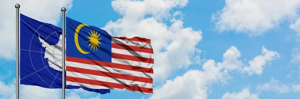 Antarctica and Malaysia flag waving in the wind against white cloudy blue sky together. Diplomacy concept, international relations. — Stock Photo, Image