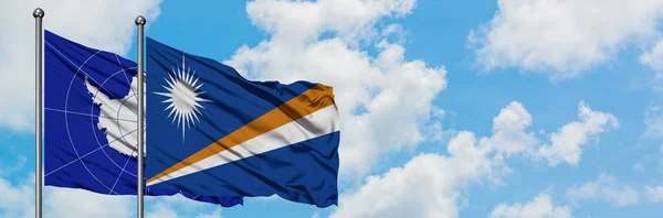 Bandeira da Antártida e Ilhas Marshall agitando no vento contra o céu azul nublado branco juntos. Conceito de diplomacia, relações internacionais . — Fotografia de Stock