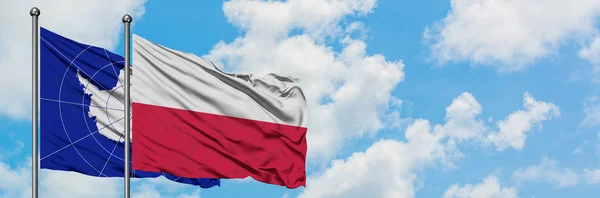 Antarktická vlajka a Polsko vlnící se ve větru proti bíle zatažené modré obloze. Diplomacie, mezinárodní vztahy. — Stock fotografie