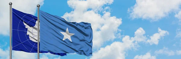 Bandera de la Antártida y Somalia ondeando en el viento contra el cielo azul nublado blanco juntos. Concepto diplomático, relaciones internacionales . — Foto de Stock