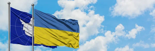 Antarktida a Ukrajina vlnící se ve větru proti bíle zatažené modré obloze. Diplomacie, mezinárodní vztahy. — Stock fotografie