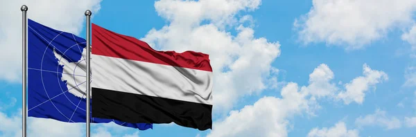 Antarctica en Jemen vlag zwaaien in de wind tegen witte bewolkte blauwe hemel samen. Diplomatie concept, internationale betrekkingen. — Stockfoto