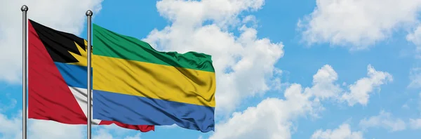 Antigua and Barbuda with Gabon flag waving in the wind against white cloudy blue sky together. Diplomacy concept, international relations. — Stock Photo, Image