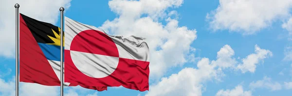 Antigua y Barbuda con bandera de Groenlandia ondeando en el viento contra el cielo azul nublado blanco juntos. Concepto diplomático, relaciones internacionales . — Foto de Stock