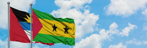 Antigua y Barbuda con la bandera de Santo Tomé y Príncipe ondeando en el viento contra el cielo azul nublado blanco juntos. Concepto diplomático, relaciones internacionales . —  Fotos de Stock