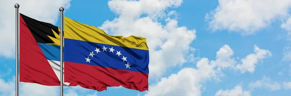 Антигуа і Барбуда з венесуельським прапором махав в вітер проти білого хмарного синього неба разом. Концепція дипломатії, міжнародні відносини. — стокове фото