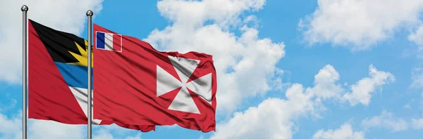 Antigua y Barbuda con Wallis y la bandera de Futuna ondeando en el viento contra el blanco cielo azul nublado juntos. Concepto diplomático, relaciones internacionales . — Foto de Stock