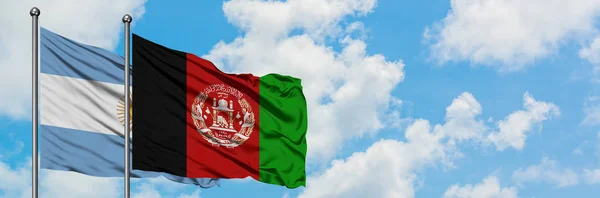 Bandera de Argentina y Afganistán ondeando en el viento contra el cielo azul nublado blanco juntos. Concepto diplomático, relaciones internacionales . — Foto de Stock