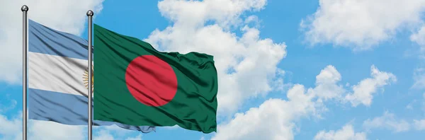 Bandera de Argentina y Bangladesh ondeando en el viento contra el cielo azul nublado blanco juntos. Concepto diplomático, relaciones internacionales . — Foto de Stock