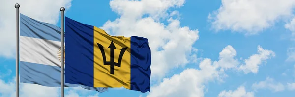Argentinien und Barbados schwenken gemeinsam die Flagge im Wind vor dem wolkenverhangenen blauen Himmel. Diplomatie-Konzept, internationale Beziehungen. — Stockfoto