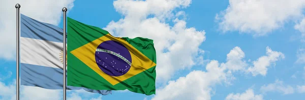 Bandeira da Argentina e do Brasil agitando no vento contra o céu azul nublado branco juntos. Conceito de diplomacia, relações internacionais . — Fotografia de Stock