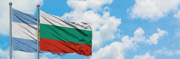 Bandera de Argentina y Bulgaria ondeando en el viento contra el cielo azul nublado blanco juntos. Concepto diplomático, relaciones internacionales . — Foto de Stock