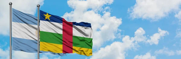 Bandera de Argentina y República Centroafricana ondeando en el viento contra el cielo azul nublado blanco juntos. Concepto diplomático, relaciones internacionales . — Foto de Stock