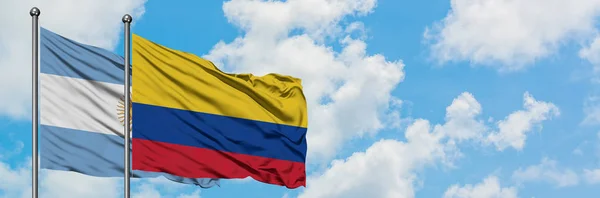 Bandera de Argentina y Colombia ondeando en el viento contra el cielo azul nublado blanco juntos. Concepto diplomático, relaciones internacionales . — Foto de Stock