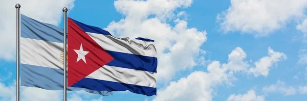 Bandeira da Argentina e Cuba agitando no vento contra o céu azul nublado branco juntos. Conceito de diplomacia, relações internacionais . — Fotografia de Stock