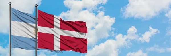 Argentina och Danmark sjunker vifta i vinden mot vit grumlig blå himmel tillsammans. Diplomatisk koncept, internationella relationer. — Stockfoto