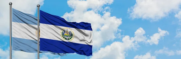 Argentinien und El Salvador schwenken gemeinsam die Flagge im Wind vor dem wolkenverhangenen blauen Himmel. Diplomatie-Konzept, internationale Beziehungen. — Stockfoto